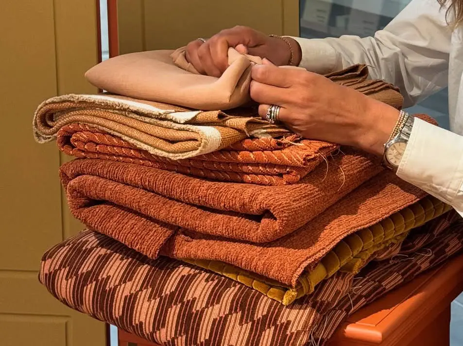 Pila di tessuti d’arredo nei toni caldi, scelti in showroom